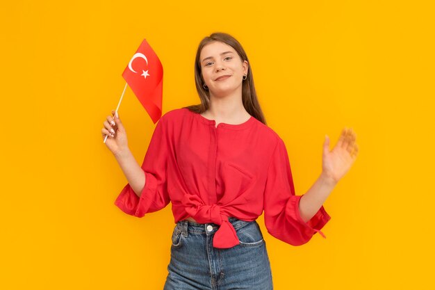 Cheerful cute girl with turkish flag in an orange photo studio portrait immigration to turkey study at universities in turkey