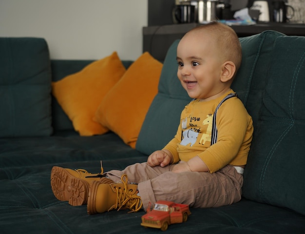 Cheerful cute kid sitting on green couch with yellow cushions