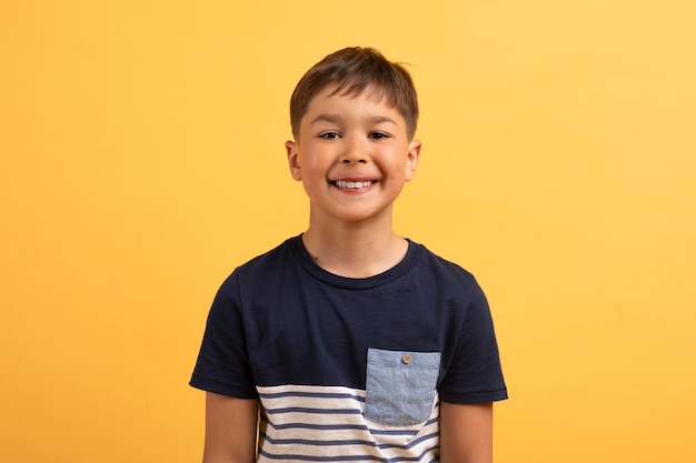 Cheerful cute school boy posing on yellow background