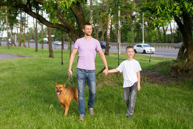 A cheerful dad holds the hand of an emotional son A dog on a leash