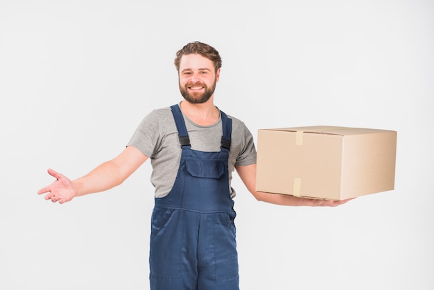 Cheerful delivery man standing with big box