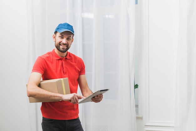 Cheerful delivery man with tablet and box