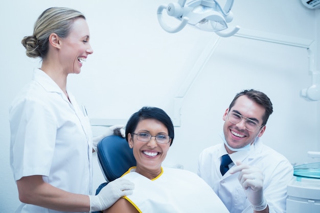 Foto dentista allegro e assistente con paziente femminile