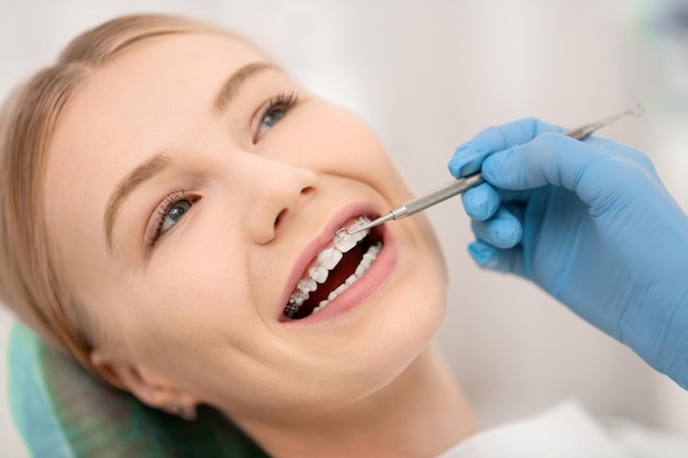 Cheerful dentists patient opening her mouth fixing her orthodontic braces in dental clinic