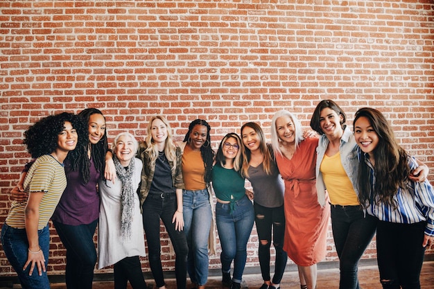 cheerful diverse women standing in front of a red brick wall