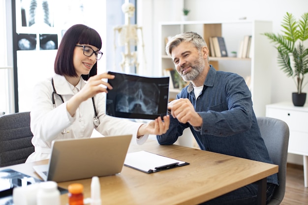 Cheerful doctor and patient holding together xray in hands