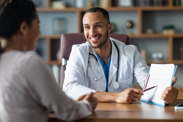 Cheerful doctor showing black lady patient treatment plan