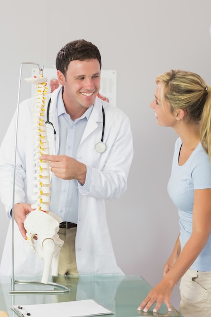 Photo cheerful doctor showing a patient something on skeleton model