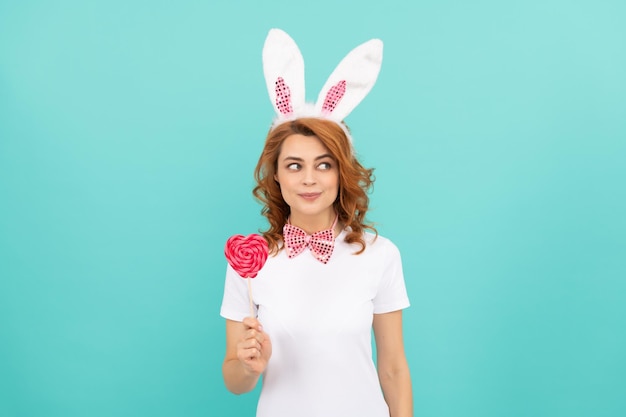 Cheerful easter woman wear bunny ears hold heart lollipop