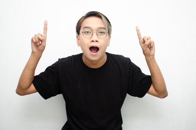 A cheerful ecstatic Asian man wears a casual black tshirt pointing and presenting to copy space