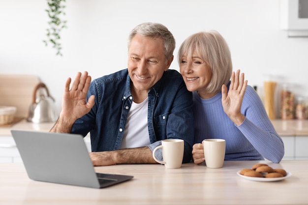 Cheerful elderly couple making video call while drinking\
coffee