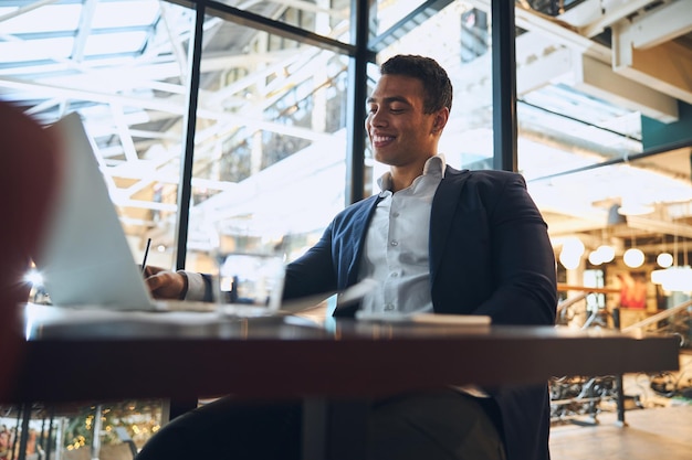 Cheerful elegant employee sitting at the laptop