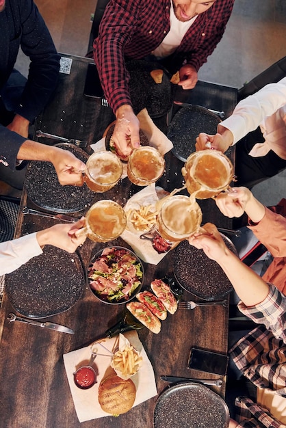 Foto emozioni allegre gruppo di giovani amici seduti insieme al bar con birra