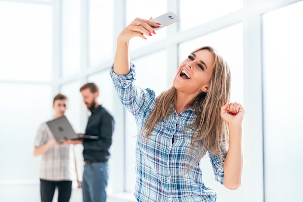 Cheerful employee takes a selfie standing in the office