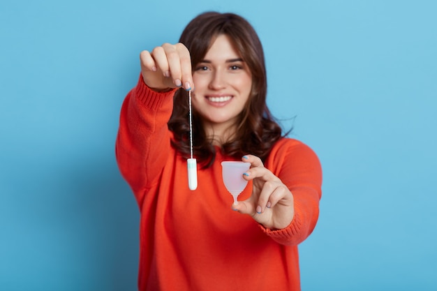 Cheerful energetic young woman recommending to use menstrual cup or tampon