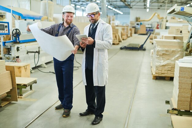 Cheerful engineer presenting blueprint to investor in white coat