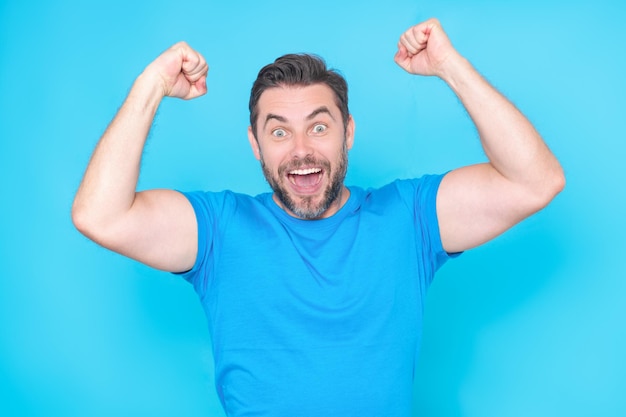 Cheerful excited man celebrating success over studio blue isolated background excited winner excited