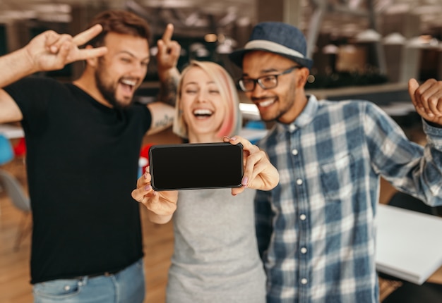 Cheerful excited young friends having fun and taking selfie