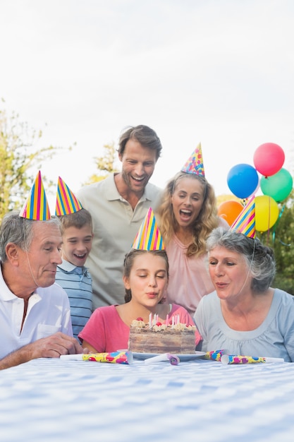 Cheerful extended family blowing out birthday candles together