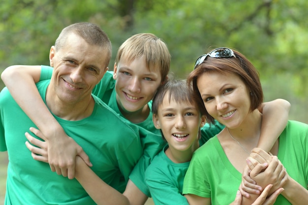 Famiglia allegra in camicie verdi che camminano nel parco estivo