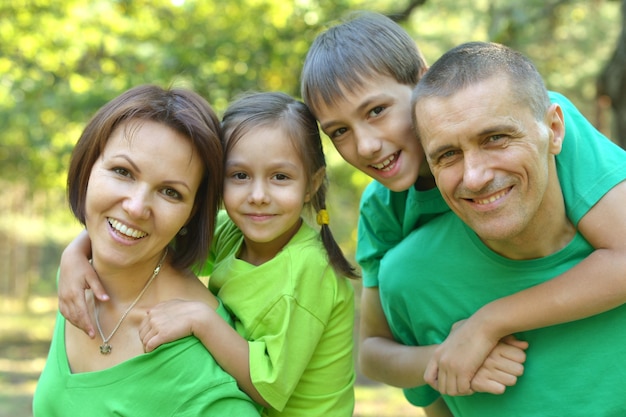 Foto famiglia allegra in camicie verdi che camminano nel parco estivo