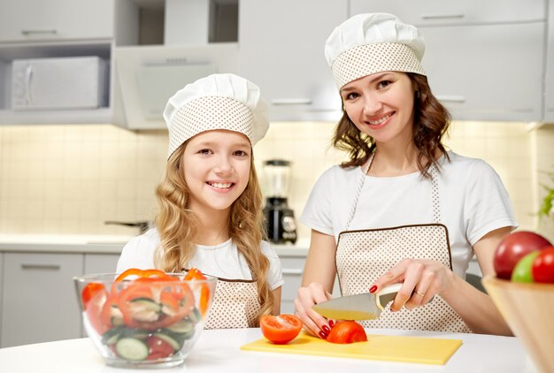 Cheerful family looking at camera while cooking salad