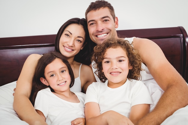 Cheerful family lying on bed against wall at home