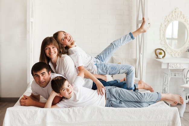 Cheerful family lying on bed looking at camera