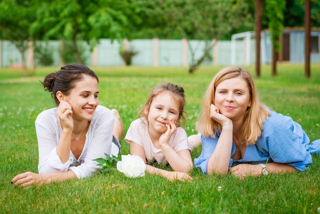공원 엄마와 딸과 할머니의 쾌활한 가족은 푸른 잔디에 누워