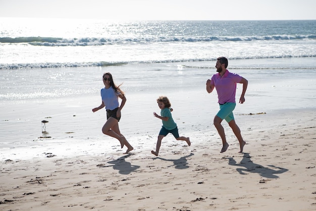 Photo cheerful family running on the beach happy mother father with child son having fun during summer holiday active parents and people outdoor activity on tropical summer holidays with children