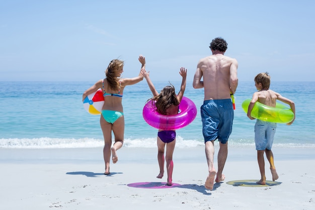 Cheerful family running towards sea with swimming equipment