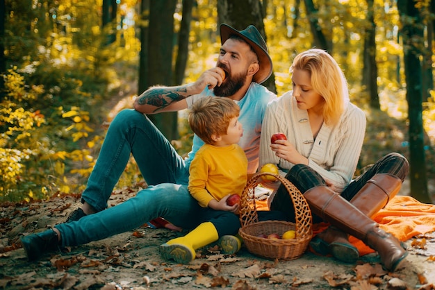 Cheerful family sitting on the grass during a picnic in a autumnal park the lights of a sun a young