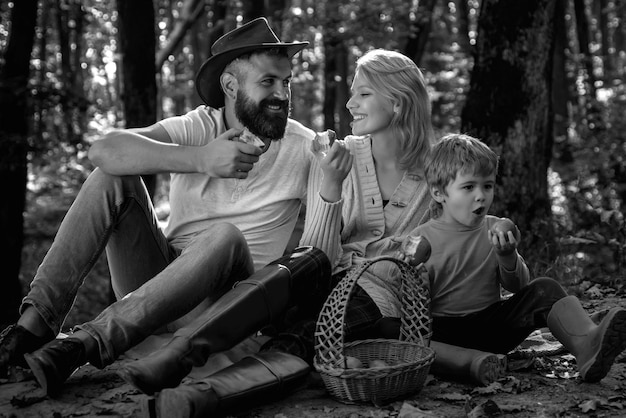 公園でのピクニック中に芝生の上に座っている陽気な家族若い笑顔の家族がピクニックをしているo