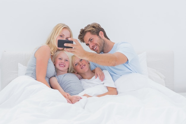 Фото Веселая семья, снимающая фотографии со смартфоном