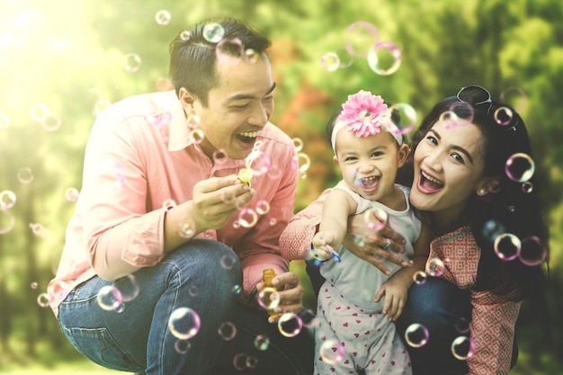 Foto famiglia allegra con bolle al parco