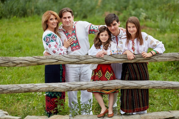 Cheerful family with kids in traditional romanian dress in a countryside park Family posing outside