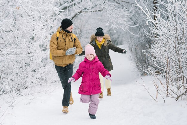 Famiglia allegra nei boschi giocando a palle di neve