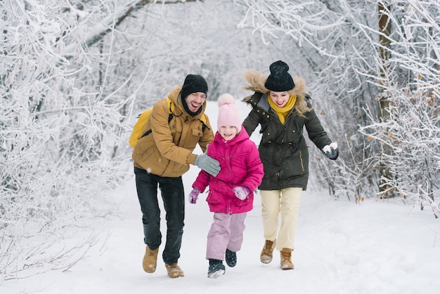 Cheerful family in the woods playing snowballs