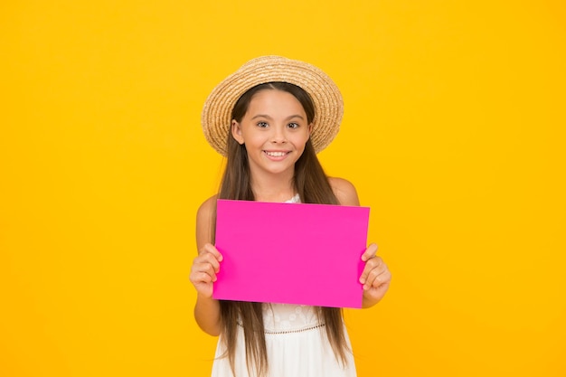 Cheerful fashion model little girl hold paper sheet beach fashion for kids small child on yellow background summer camp activity copy space summer vacation and holiday happy childhood