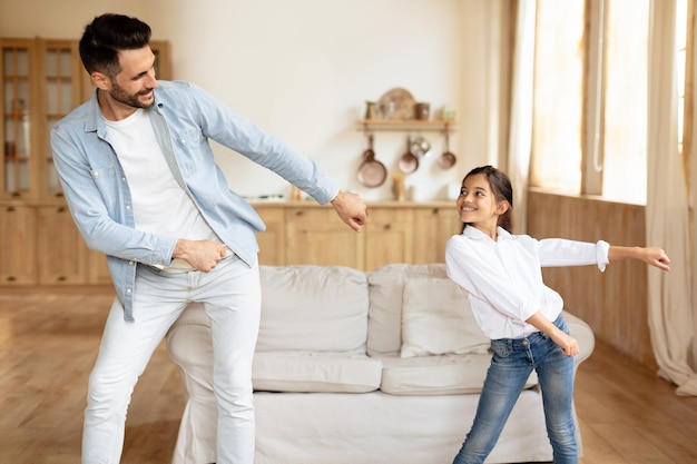 Cheerful father and daughter girl moving and dancing indoors