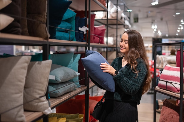 cheerful female customer choosing cushion