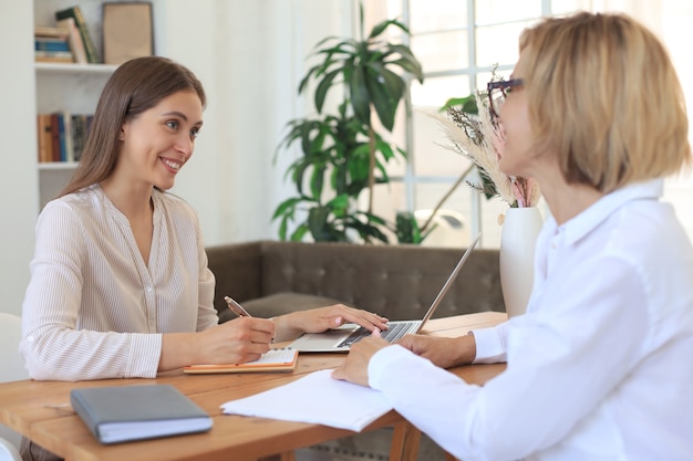 Cheerful female doctor psychologist shaking grateful patient hands after having a consultation meeting.