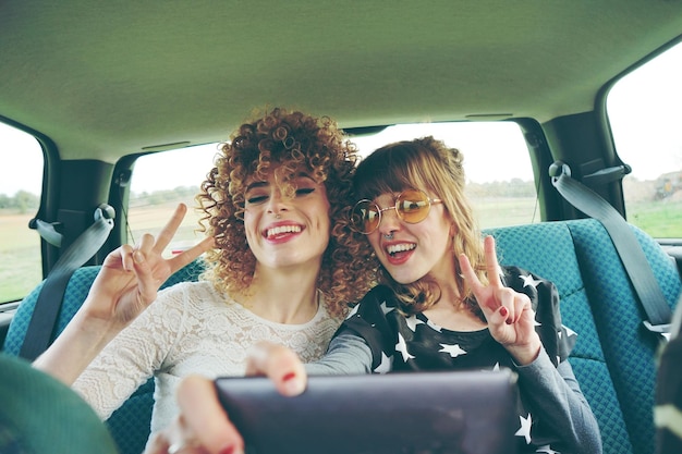 Foto amici donne allegre che si fanno un selfie sedute in macchina