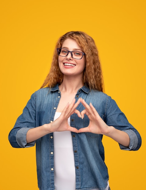 Cheerful female gesturing heart and smiling