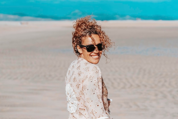 Веселая туристка, наслаждающаяся днем на пляже во время летних каникул, смотрящая в камеру Портрет взрослой женщины, улыбающейся и веселящейся на свежем воздухе Концепция счастья