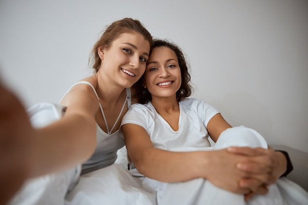 Cheerful females expressing positivity while spending their weekend together, posing on camera