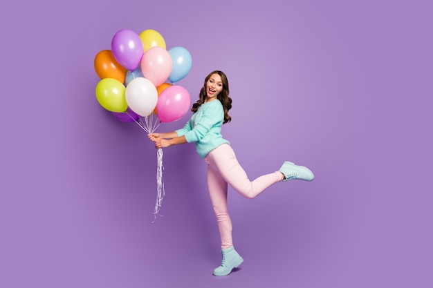 cheerful feminine girl hold many baloons enjoy festive woman day event scream wear turquoise pastel sweater pink footwear.