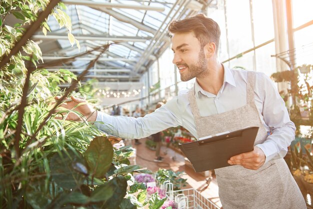 Cheerful florist checking the assortment in his flower shop