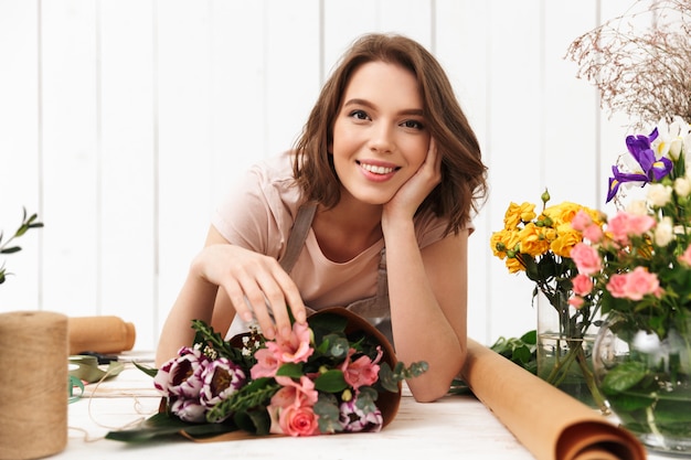 Cheerful florist woman with flowers in workshop