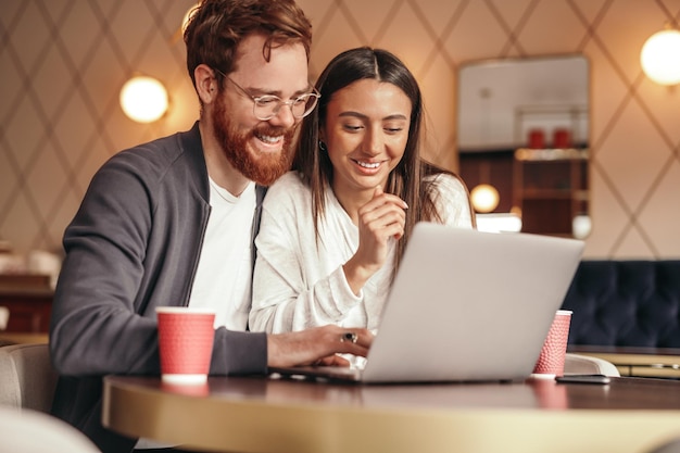 Foto liberi professionisti allegri che usano il laptop nella caffetteria